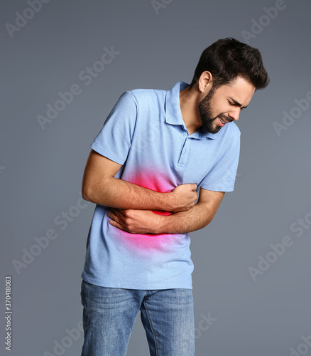 Man suffering from stomach pain on grey background