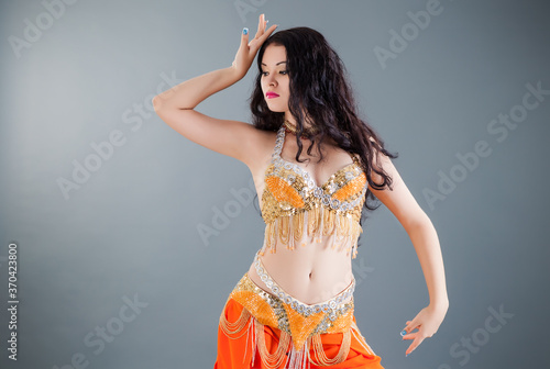 attractive brunette young woman poses in handmade orange belly dancer costume