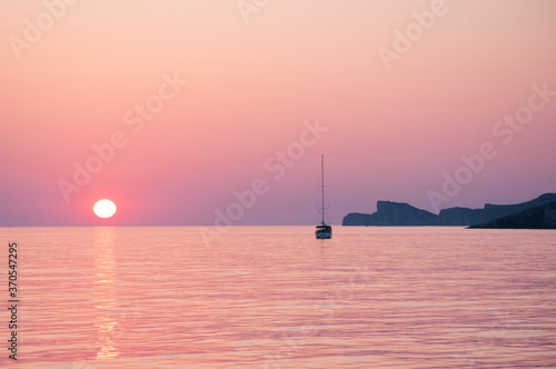 Samotny jacht na tle zachodu słońca na spokojnym morzu