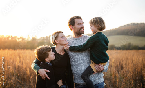 Beautiful young family with small children on a walk in autumn nature.