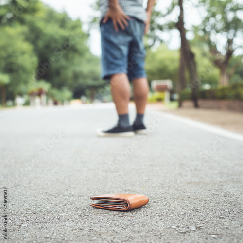 Man lose brown wallet on the road in tourist attraction. Losing wallet concept. Focus on wallet