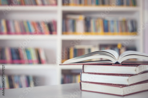 Book stack on the table in the library room and blurred space of bookshelf background