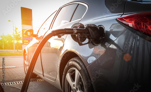 Person pumping gas. Fuel petrol for car at gasoline oil station nozzle in tank. Hand and black refueling gun close-up.