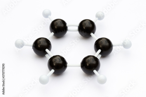 Plastic ball-and-stick model of a benzene molecule (C6H6) on a white background. The molecule is shown with kekule structure. Shallow depth of field.