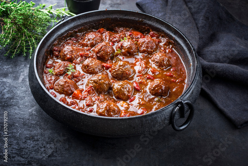 Traditional slow cooked American Tex Mex meatballs chili with mincemeat and beans in a spicy sauce offered as close-up in a design cast-iron roasting dish