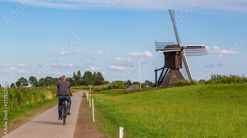 Tourist passing Windmill the Monnikenburenmolen or Nijhuizumermolen a drainage mill in Nijhuizum, Friesland, Netherlands.