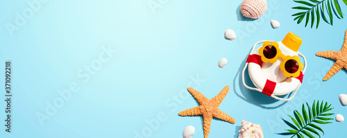 Sunblock bottle wearing sunglasses with starfish and seashells - flat lay