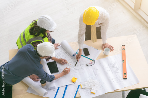 Team of engineers and architects working, planing, measuring layout of building blueprints in construction site. top view