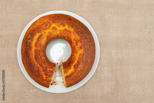 Cornmeal Cake (Bolo de Fuba) cut Brazilian style on a white plate. Isolated on jute. Top view. Copy space. Horizontal shot