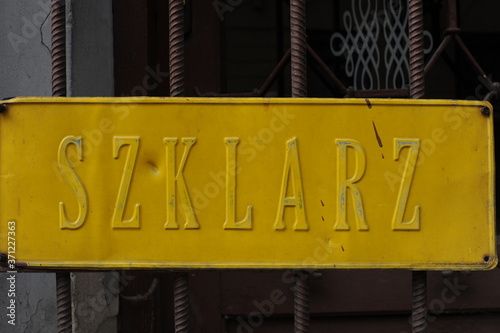 Old shiny golden plate on the door to a workshop of glazier in Poland (Polish word "Szklarz" means glazier or glassmaker in English)