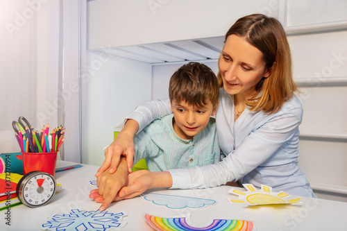 Boy with autism learn weather using cards, teacher hold hands and point to correct one