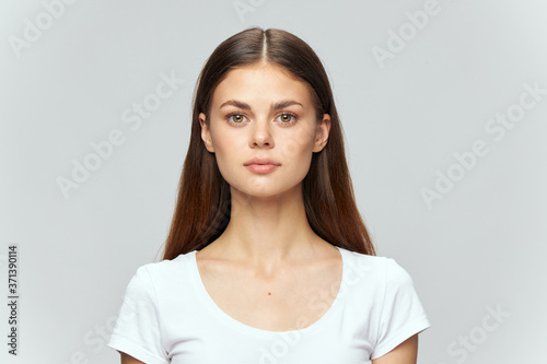 Portrait of a girl in a white T-shirt on a gray background cropped view
