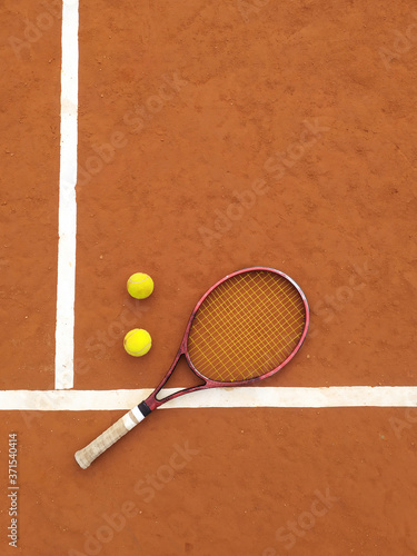 Raqueta y dos pelotas de tenis en una cancha de tenis de polvo de ladrillos