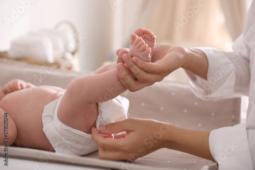 Mother changing her baby's diaper on table, closeup