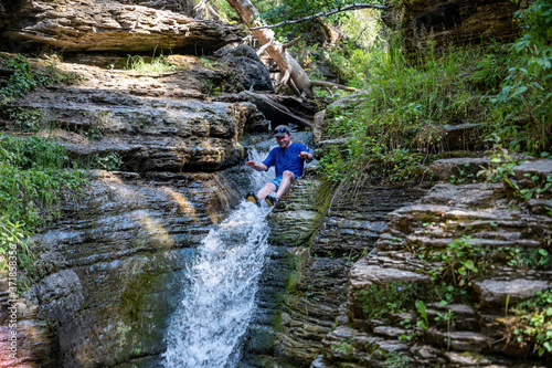 Caucasian male on rock waterslide into Devils bathtub in Spearfish Canyon of the Black Hills South Dakota