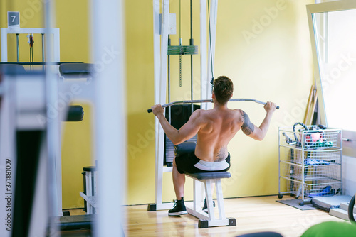 Fit man on lat pull down machine at the health club. Work out on Pull down Weight Machine