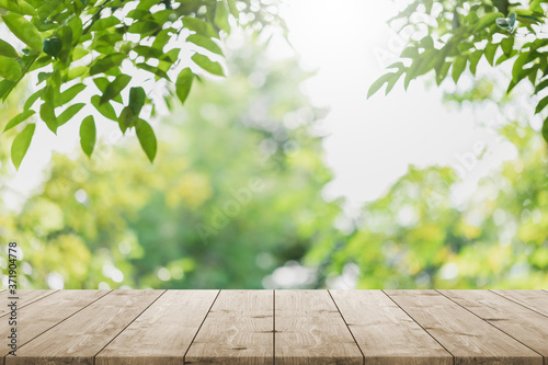 Empty wood table top and blurred green tree in the park garden background - can used for display or montage your products.