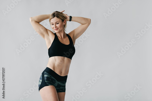 Slender figure. Happy woman with smart watch demonstrates biceps and muscular body