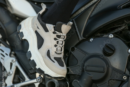 sneakers on female legs on motorcycle background close up
