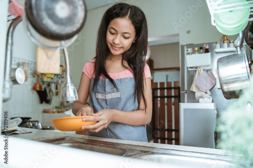 teenage girls happily do the household chores washing dishes doing activities during the pandemic at home