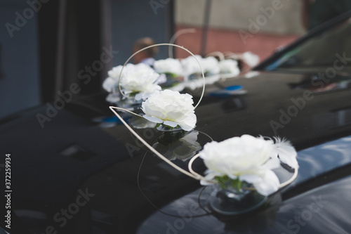 Ozdoby weselne na aucie. Samochód ślubny przystojony w kwiaty. Maska auta w dekoracjach małżeńskich