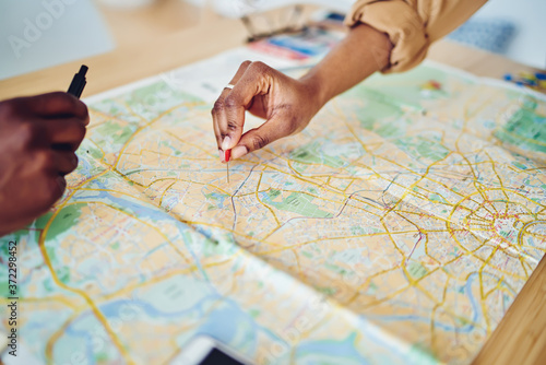 Cropped image of woman's hand pointing on mark on cartography planning adventure route on journey, top view of map of country checking direction and location for explore during travel vacation.