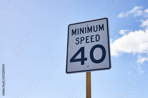 40 mph minimum speed sign on a highway to keep a smooth traffic flow. Speed zone traffic sign against blue sky and clouds.