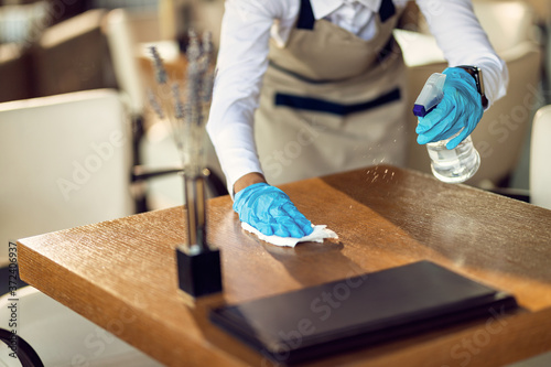 Close-up of waitress disinfecting tables in a cafe.