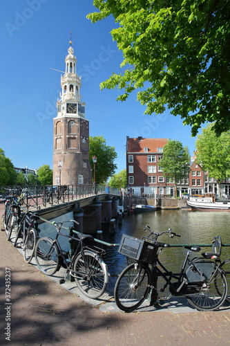 Montelbaanstoren Tower (built in 1516), located along Oudeshans canal in Amsterdam Centrum, with a bridge, bicycles and a cobbled pavement in the foreground, Amsterdam, Netherlands