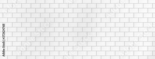 Wall made of white ceramic tiles. Background and texture. Large wide background for a banner. Tiles laid on a brick. Bright lit background.