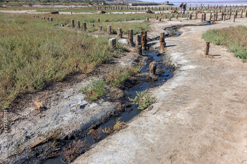 Spilled streams of liquid crude oil flow down drainage ditch into public body of water. Environmental disaster Oil pollution of environment from obsolete technologies and ancient production equipment