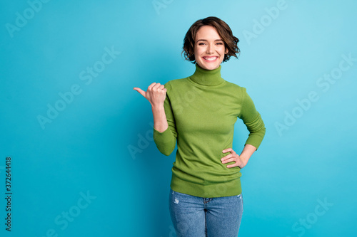 Portrait of positive cheerful girl promoter point thumb finger copyspace demonstrate way adverts promo wear good look clothes isolated over blue color background