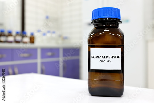 Selective focus of formaldehyde or formalin in brown amber glass bottle inside a laboratory. Blurred background with copy space.