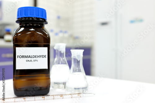 Selective focus of formaldehyde or formalin in brown amber glass bottle inside a laboratory. Blurred background with copy space.