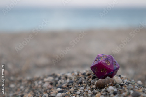 Purple Pink Dungeon and Dragons dice with character sheets at the beach