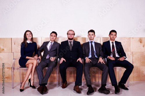 Full length portrait of a multi ethnic people dressed in corporate clothes waiting for start interview, young skilled intelligent workers resting after business meeting with their partners, copy space
