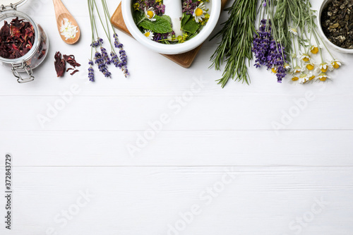 Flat lay composition with healing herbs on white wooden table. Space for text
