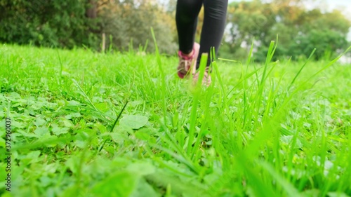 The girl in red sneakers is on the green grass in the direction of the camera.