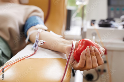 Close-up of patient with tubes in her arm squeezing the ball in her hand while donating the blood