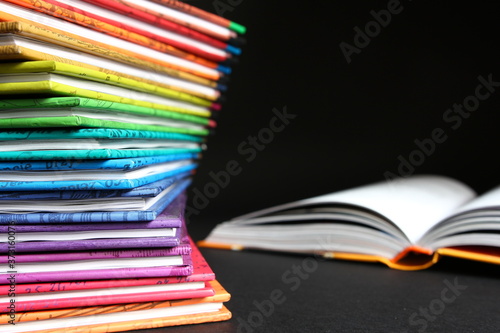 Edukacja - lektury szkolne, książki ułożone jedna na drugą w kolorach tęczy na ciemnym tle