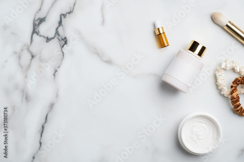 Natural skincare cosmetic products on white marble desk. Flat lay, top view body lotion, serum essential oils, moisturizer cream jar, female accessories.