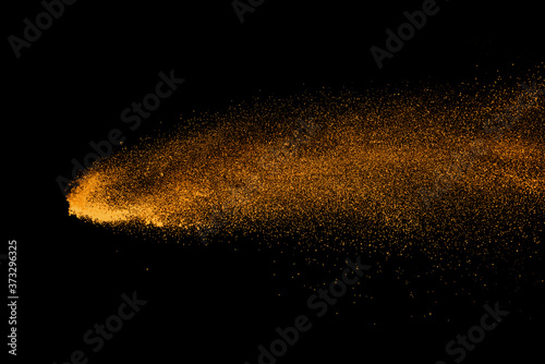 Closeup of orange powder particle splash isolated on black background.
