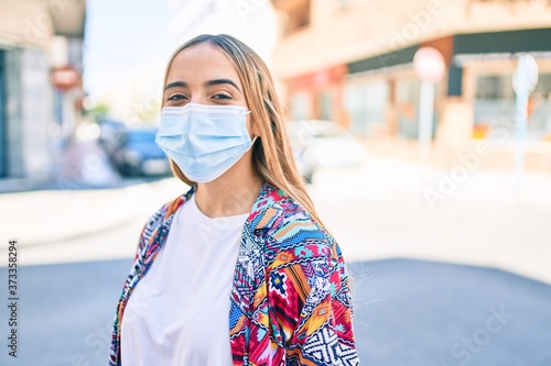 Young beautiful blonde caucasian woman smiling happy outdoors on a sunny day wearing coronavirus safety mask