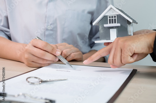 A real estate agent with rental homes and home insurance for clients to sign contracts under a formal home lease agreement. Home rental and insurance concept
