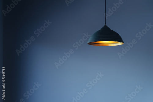 vintage style hanged ceiling lamp warm orange tone light color bulb light with dark blue tone dirty concrete background wall.