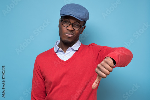 African man giving thumbs down gesture, looking with negative facial expression