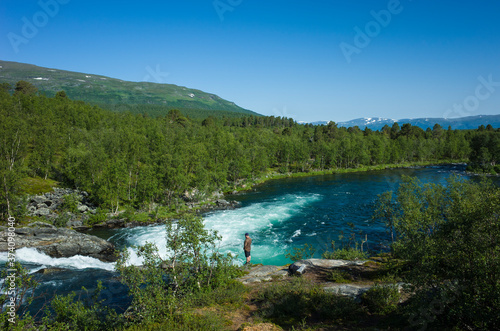 Nature of Scandinavia in summer. Man tourist standing near Abiskojokk river in Abisko National Park in northern Sweden. Sunny day