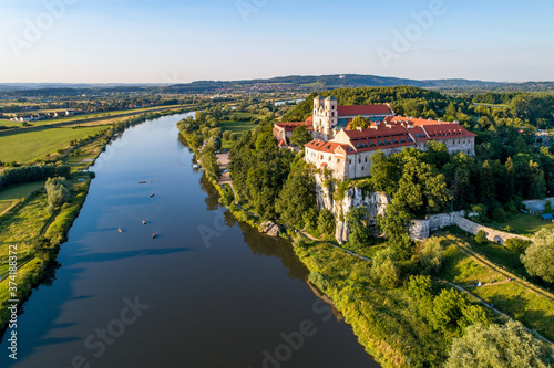 Tyniec near Krakow, Poland. Benedictine abbey, monastery and church on the rocky cliff and Vistula river with canoes and kayaks. Aerial view at sunset. Bielany monastery far in the background