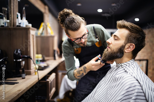 Happy young handsome man visiting hairstylist in barber shop salon