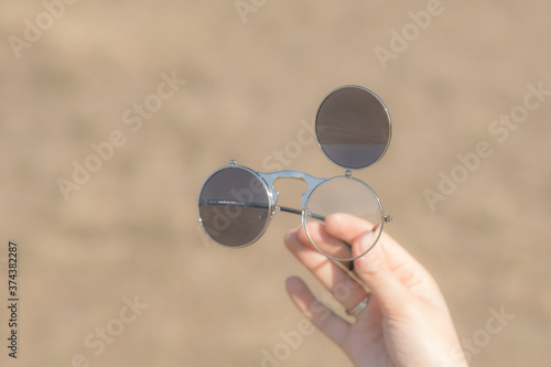 Steampunk sunglasses held in hand with round lenses retro flip up model close up shoot in a summer day. Selective focus